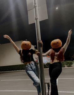 two women with pumpkin heads hanging from a pole