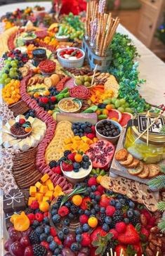 a table topped with lots of fruit and crackers next to other foods on top of it