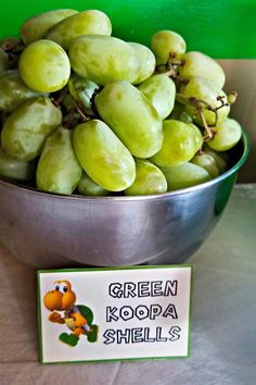 green grapes in a metal bowl next to a sign that says green kopa shells