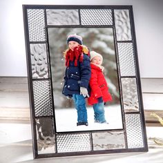 two children are standing in front of a glass photo frame with snow on the ground