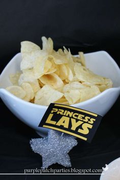 a white bowl filled with chips sitting on top of a black table next to a bottle