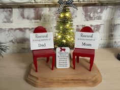 two red chairs sitting next to a small christmas tree on top of a wooden table