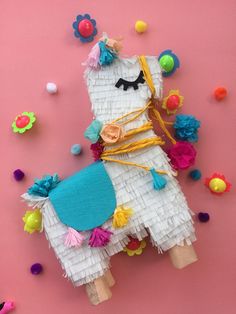 a llama made out of tissue paper and pom poms on a pink background