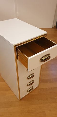 a white and gold file cabinet sitting on top of a hard wood floor