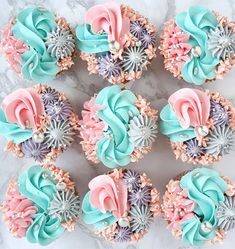 cupcakes decorated with pastel colors and flowers on a marble table top, ready to be eaten