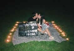 a man and woman kissing on a blanket with lights