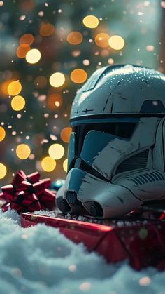 a star wars helmet sitting on top of a pile of snow next to a christmas tree