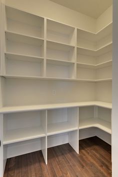 an empty room with white shelving and wood flooring in the middle of it