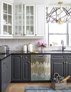 a kitchen with black and white cabinets, gray counter tops and gold accents on the backsplash