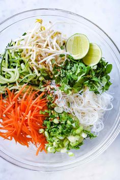 the ingredients for this salad in a glass bowl are mixed with carrots, celery, and lime