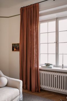 a white chair sitting next to a window in front of a radiator and heater