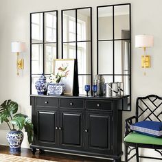 a black cabinet with mirrors and vases on it