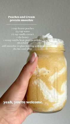 a hand holding a jar filled with cream and whipped toppings on top of it