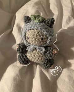 a small crocheted teddy bear laying on top of a bed