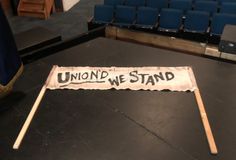 a sign that says, union we stand in front of an empty stage with blue seats