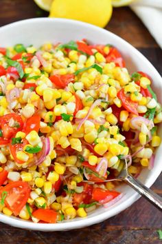 a white bowl filled with corn and red onion salad on top of a wooden table