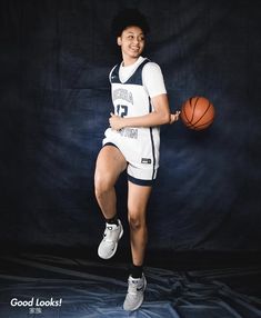 a young man holding a basketball while standing in front of a black background with the words good looks on it