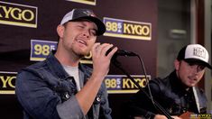 two young men singing into microphones at a press conference