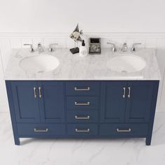 two white sinks sitting next to each other on top of a blue vanity with gold handles