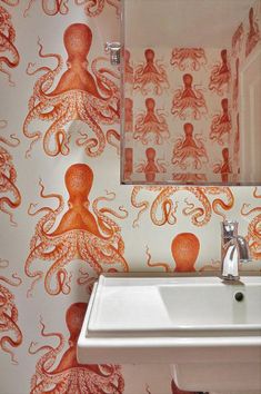 an orange octopus wallpaper in a bathroom with a white sink and mirror above it