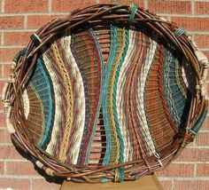 a large woven basket sitting on top of a wooden table next to a brick wall