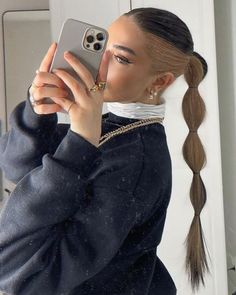 a woman taking a selfie in the mirror with her cell phone and ponytails