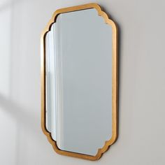 a mirror mounted to the side of a white wall next to a wooden framed object