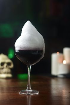 a glass filled with liquid sitting on top of a wooden table next to a candle