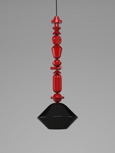 a red and black glass light hanging from a ceiling fixture in the shape of a pyramid