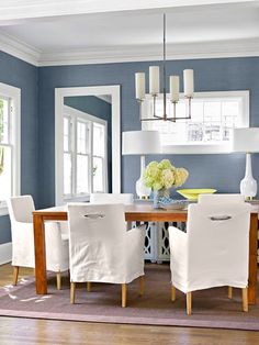 a dining room with blue walls and white chairs