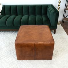 a green velvet couch and footstool in a living room with white rugs