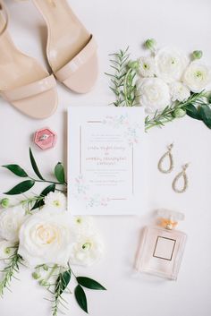 the wedding stationery is laid out with shoes, flowers and jewelry on top of it