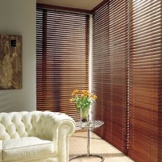 a white couch sitting next to a window with wooden blinds on the windowsills