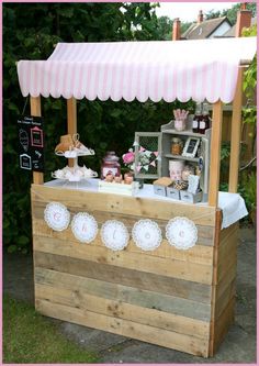 an outdoor ice cream stand with pink and white striped awning on the top that says, that cute little cake