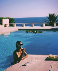 a man sitting on the edge of a swimming pool