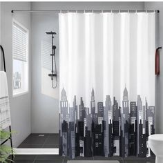 a bathroom with a shower curtain that has city buildings on it and a white toilet in the corner