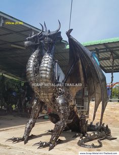 a large metal dragon statue sitting on top of a cement slab in front of a building