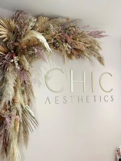 a sign that says chic aesthetics on the side of a wall with dried flowers