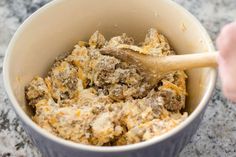 a person mixing food in a bowl with a wooden spoon