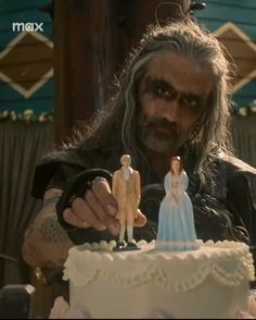 a man with long hair holding a cake in front of him and looking at it