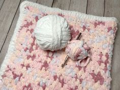 a crocheted blanket with a ball of yarn next to it