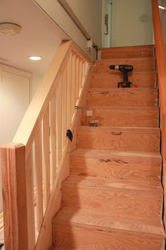 a wooden stair case with tools on the handrail and wood flooring under it