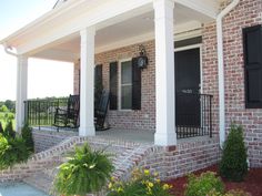 the front porch of a brick house with black shutters