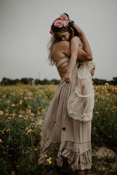 two women hugging each other in the middle of a field with flowers on her head