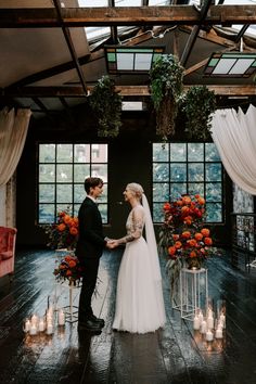 a bride and groom standing in front of candles