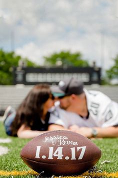 a football laying on top of a green field next to a woman and a man