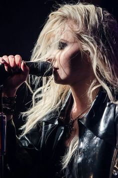 a black and white photo of a woman with long hair holding a microphone to her mouth