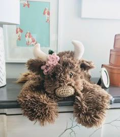 there is a stuffed animal with horns and flowers on it's head sitting on a dresser