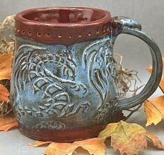 a blue and brown mug sitting on top of leaves