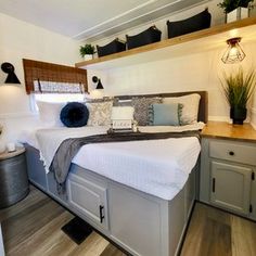 a bed sitting in the middle of a bedroom next to a dresser and window with potted plants on top of it